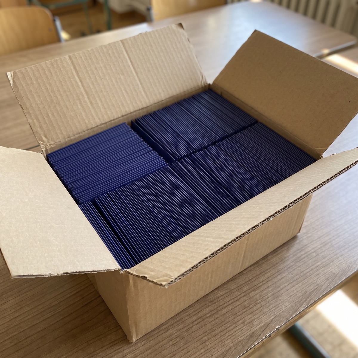 Symbolbild (mit KI erstellt): offener Karton voller AbiKarten-Packs